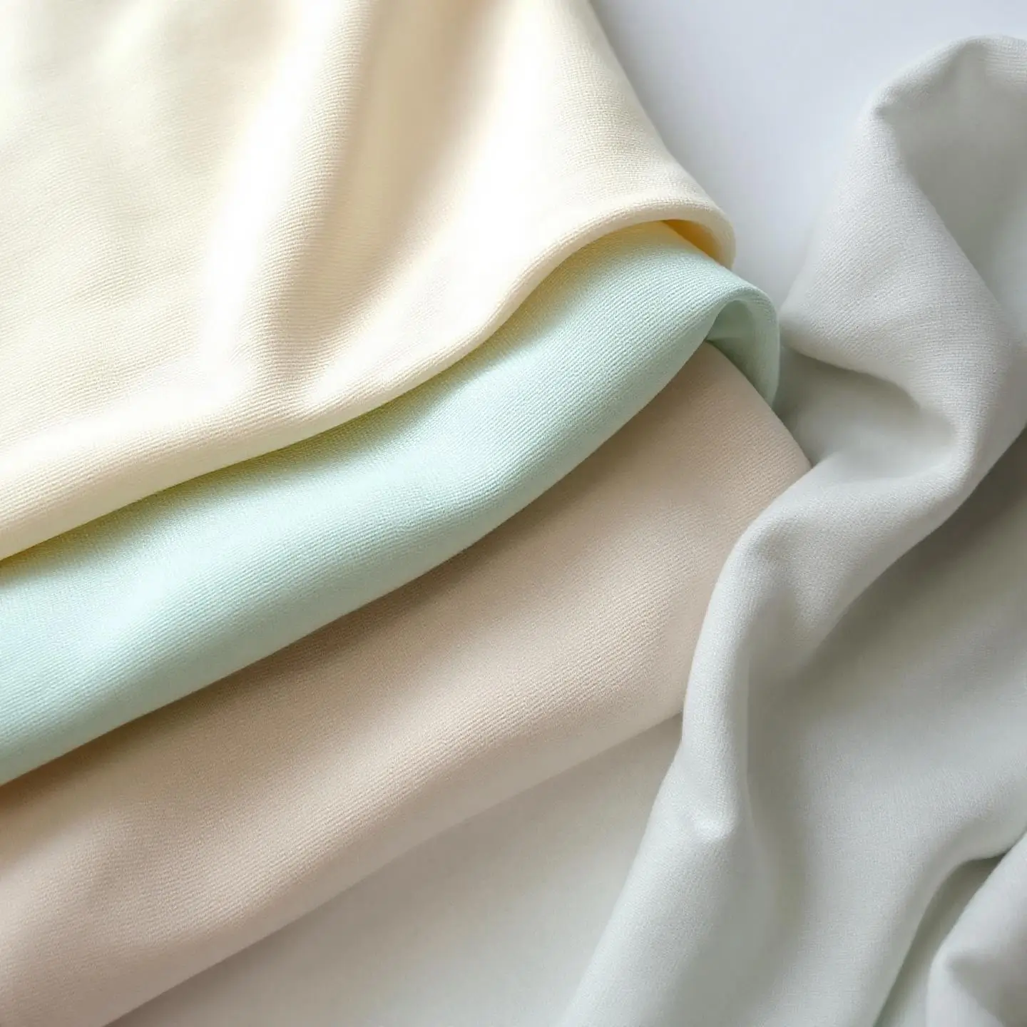 Assortiment de textures de textiles naturels doux pour bébé : coton biologique, gaze, bambou, mousseline.